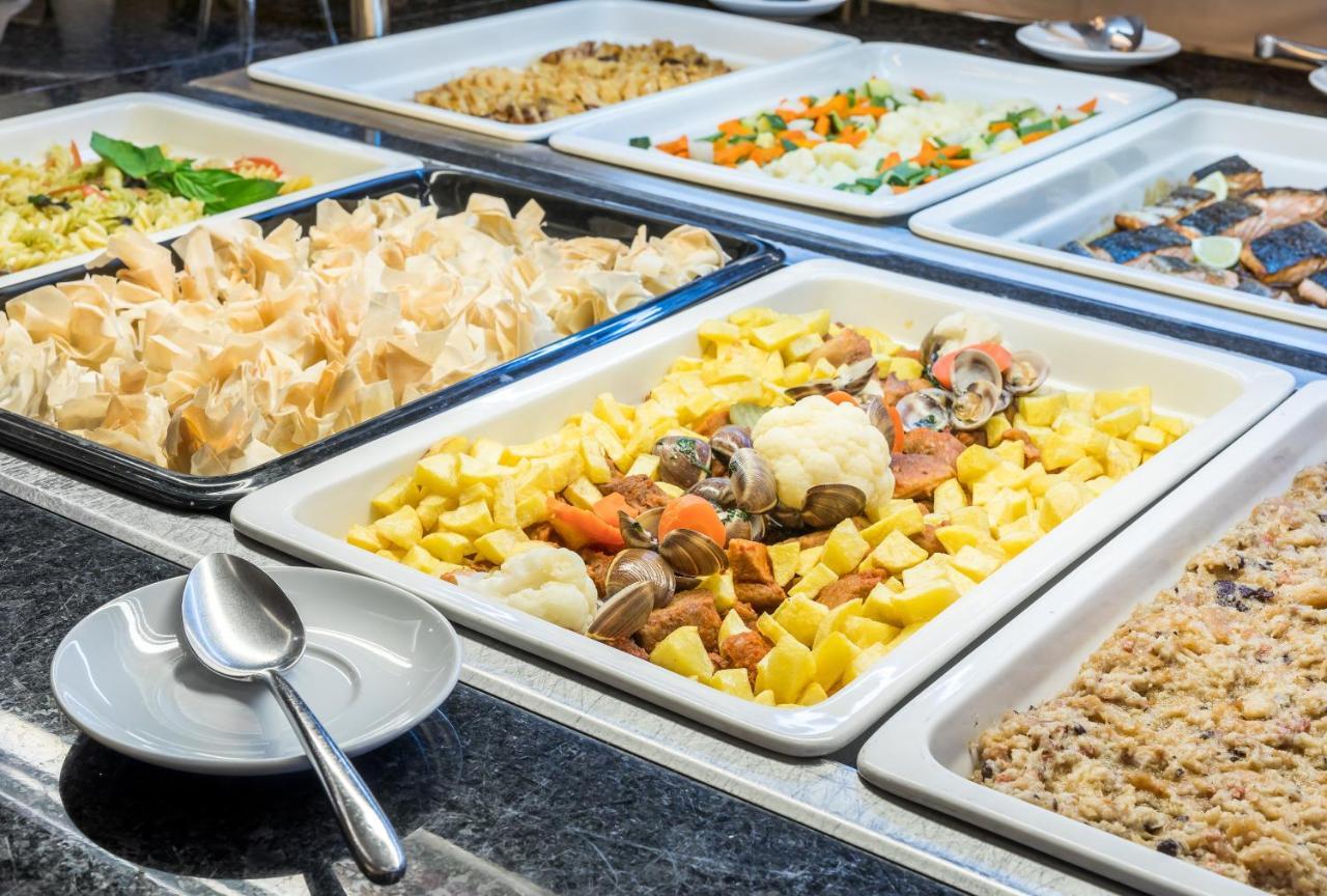 Ap Lago Montargil - Conference & Spa Exterior photo The photo shows a buffet-style display of various dishes. There are several rectangular trays filled with different types of food. 

1. One tray contains a mix of vegetables and seafood, likely including potatoes and cauliflower.
2. Another tray hold